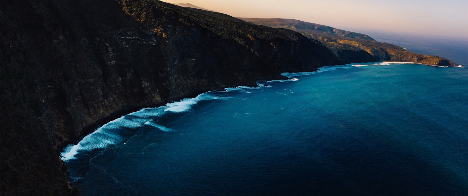 Aerial view of cliffs falling into a turquoise sea